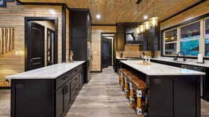 A modern kitchen with wooden paneling, black cabinets, and a central island with seating.