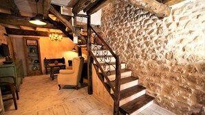 A rustic interior with a wooden staircase, a chandelier, and a herringbone-patterned floor.