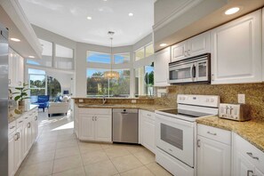 A modern kitchen with white cabinetry, a built-in microwave, a toaster, and a dishwasher. - Sunny Retreat with Private Pool in North Naples (Naples)