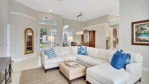 A spacious living room with a large sectional sofa, a coffee table, and a dining area with a chandelier.