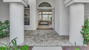 A covered entrance with a brick pathway leading to a room with a window and a door.