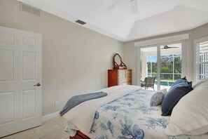 A bedroom with a bed, a dresser, and a view of a pool through a sliding glass door. - Sunny Retreat with Private Pool in North Naples (Naples)