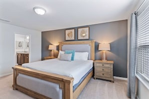 A bedroom with a wooden bed, bedside lamps, a nightstand, and a framed picture on the wall. - 5BR Townhouse w/ Private Pool & Mickey-themed Room (Davenport)