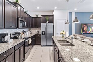 A modern kitchen with dark cabinetry, stainless steel appliances, and a granite countertop. - 5BR Townhouse w/ Private Pool & Mickey-themed Room (Davenport)