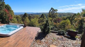 Ein Whirlpool auf einer Holzterrasse mit herrlichem Blick auf Wald und Berge.