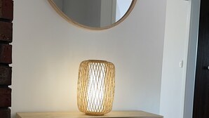 Un meuble-lavabo de salle de bain avec un miroir rond et un luminaire tressé.