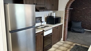 Une cuisine avec des meubles de rangement en bois foncé, un réfrigérateur en acier inoxydable, un four à micro-ondes et une cuisinière.