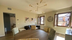 A dining area with a round table, patterned chairs, a chandelier, and artwork on the walls. - Ca' Magna Apartment  (Venezia)