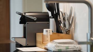 Un coin cuisine équipé d’une machine à café, d’ustensiles, d’un distributeur de serviettes et d’un reçu posé sur le comptoir.