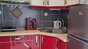 A kitchen with red cabinets, a stainless steel refrigerator, and a microwave. - Agréable Studio Avec Cave et Parking Privatifs (La Ciotat)