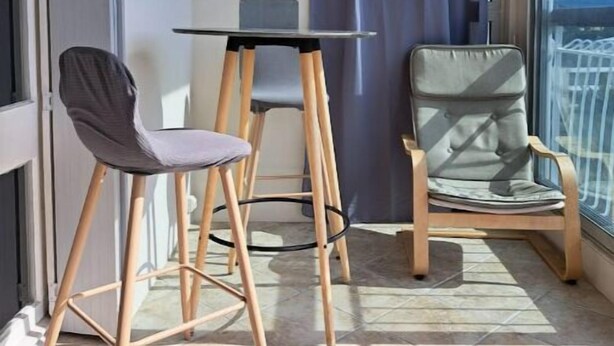 A balcony with a table and two chairs, a view of the city, and a curtain. - Agréable Studio Avec Cave et Parking Privatifs (La Ciotat)