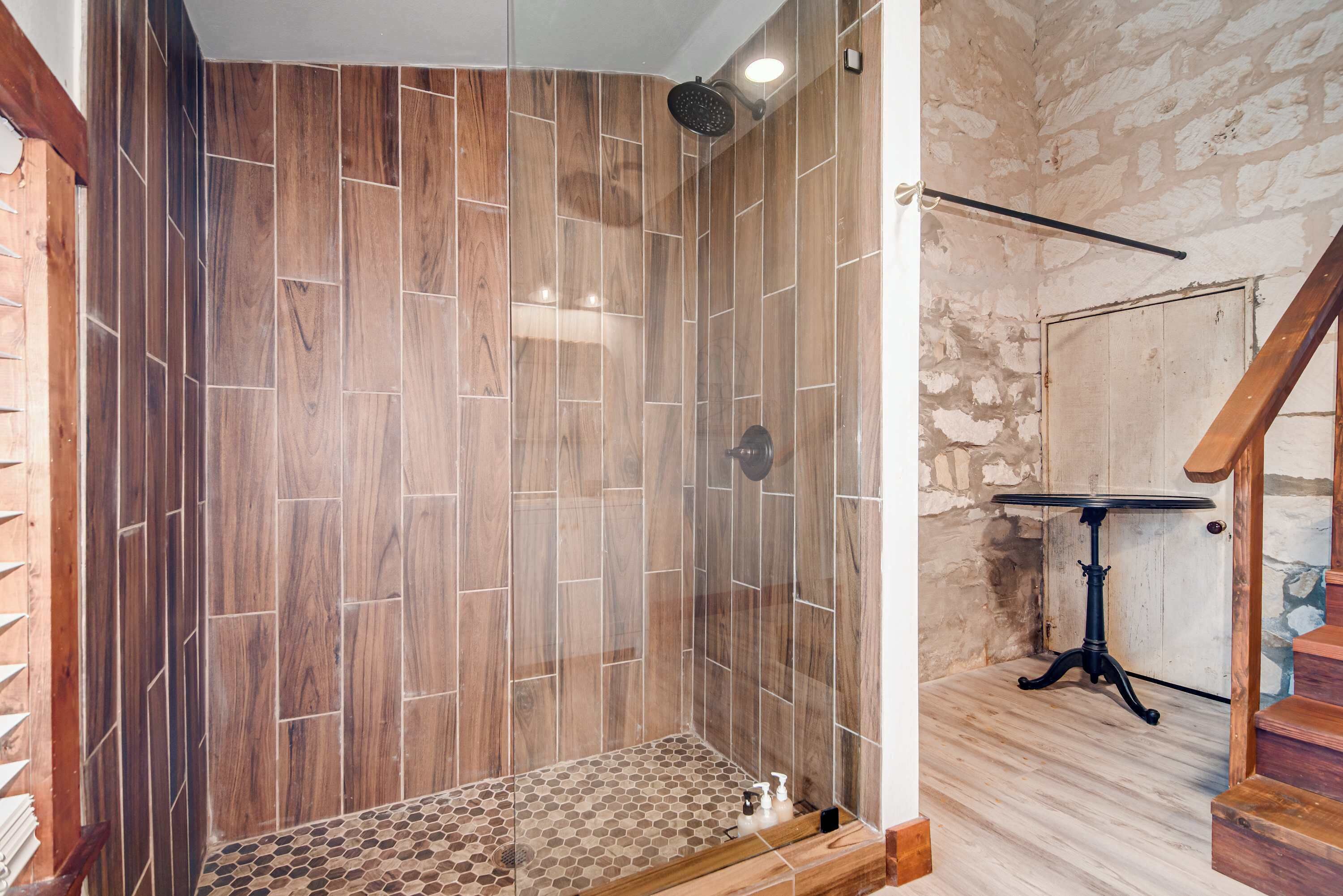 A shower with wooden paneling and a glass door.