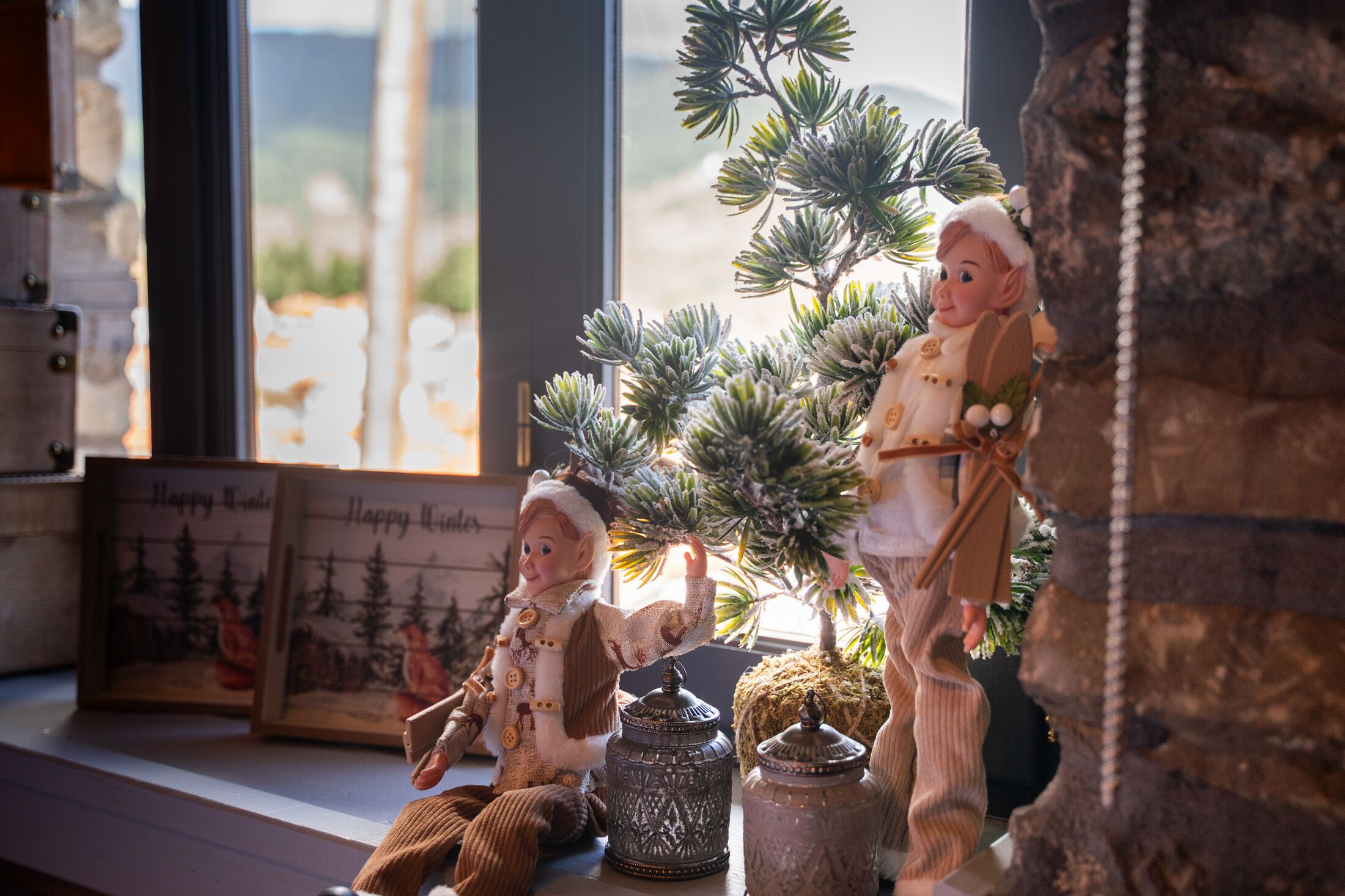 Une étagère ornée de divers objets décoratifs, notamment des figurines, un petit arbre et un tableau encadré.