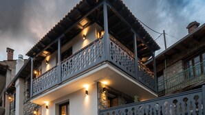 Un bâtiment à deux étages, doté d’une façade en pierre, de balcons avec des garde-corps décoratifs et d’un éclairage extérieur.