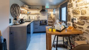 Une cuisine moderne avec une grande horloge, des appareils électroménagers intégrés et un mur décoratif en pierre.
