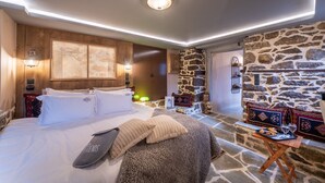 Une chambre avec un grand lit, un mur en pierre et une petite table avec des collations.