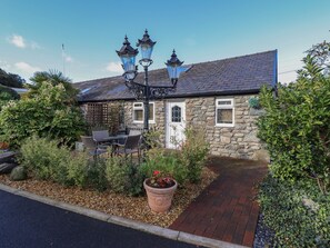 A stone house with a garden, outdoor seating, and a street lamp.