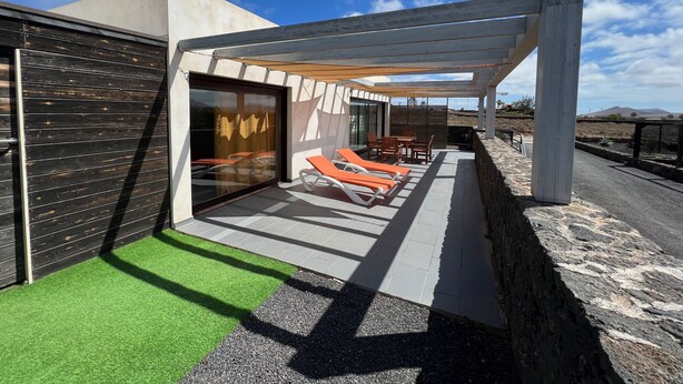 Eine moderne Außenpatio mit Sitzgruppe, überdachtem Bereich und Blick auf die umliegende Landschaft.