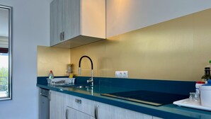 Eine moderne Küche mit blauer Arbeitsplatte, Edelstahlgeräten und einer goldfarbenen Spritzschutzwand.
