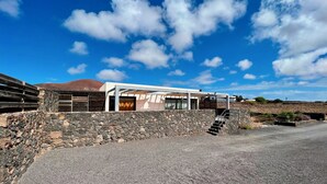 Ein modernes Haus mit einer Steinsäule, einer Holzterrasse und einem strahlend blauen Himmel.