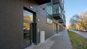 A modern building with large windows, a covered entrance, and a parking area with cars. - Tastefully Arranged Studio by Renters (Wroclaw)
