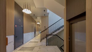 A modern hallway with marble flooring, a staircase with metal railings, and a wooden door. - Tastefully Arranged Studio by Renters (Wroclaw)