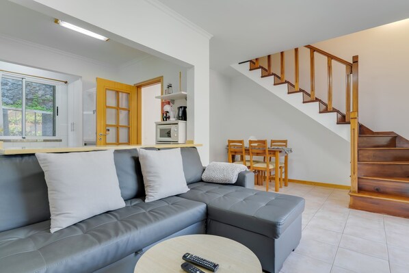 Una sala moderna con un sofá seccional gris, una mesa de centro y una escalera con barandillas de madera.