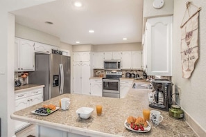 A modern kitchen with white cabinets, stainless steel appliances, and a breakfast setup on the counter.