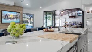 A modern kitchen with a marble countertop, a fruit bowl, and a wooden cutting board. - Kayaks, Boat Dock, Heated Pool & Spa, Outside Kitchen, Tiki Hut - Villa Pedro - Roelens Vacations (Cape Coral)
