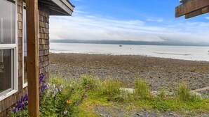 A wooden building with a view of a rocky beach and calm water. - Rustic Roots Seaside Blush Cabin (ADA) (Seward)