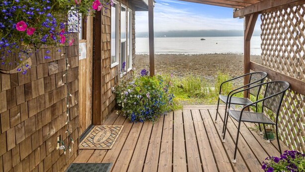 A wooden deck with a view of the ocean, a wooden pergola, and a seating area with chairs. - Rustic Roots Seaside Blush Cabin (ADA) (Seward)