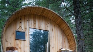 A wooden cabin with a large door, a small window, and a wooden bench outside. - Salted Roots Purple Door Cottage with Ocean Views (Seward)
