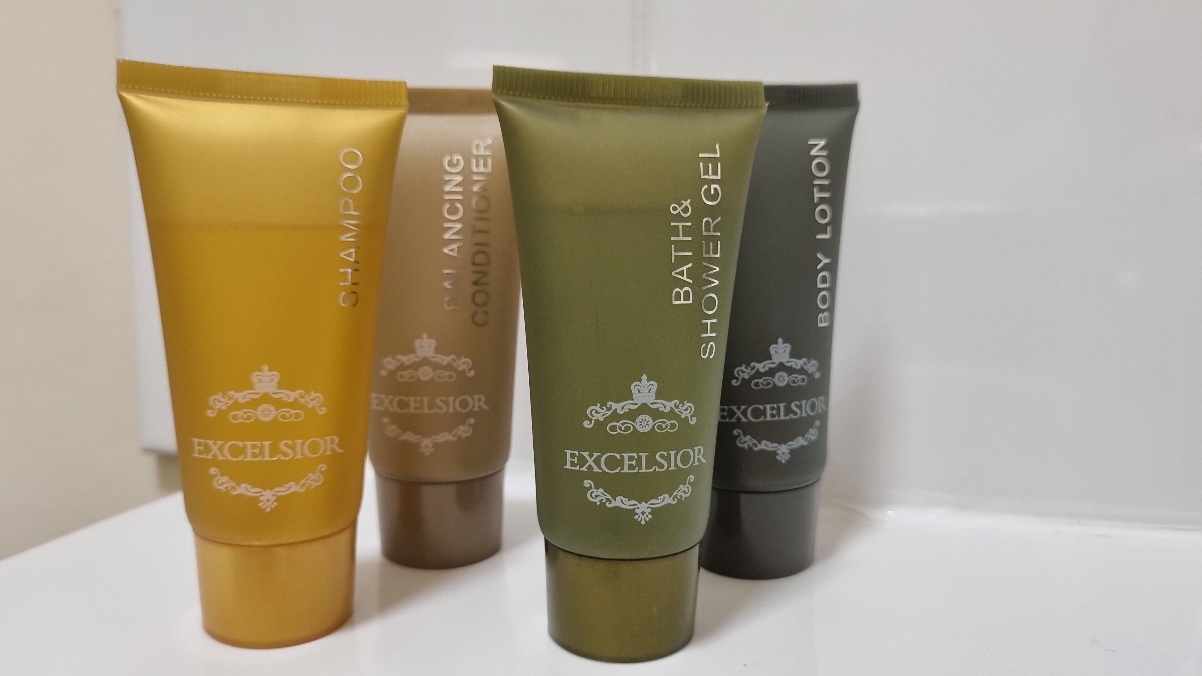 Four tubes of Excecilior body care products in different colors.