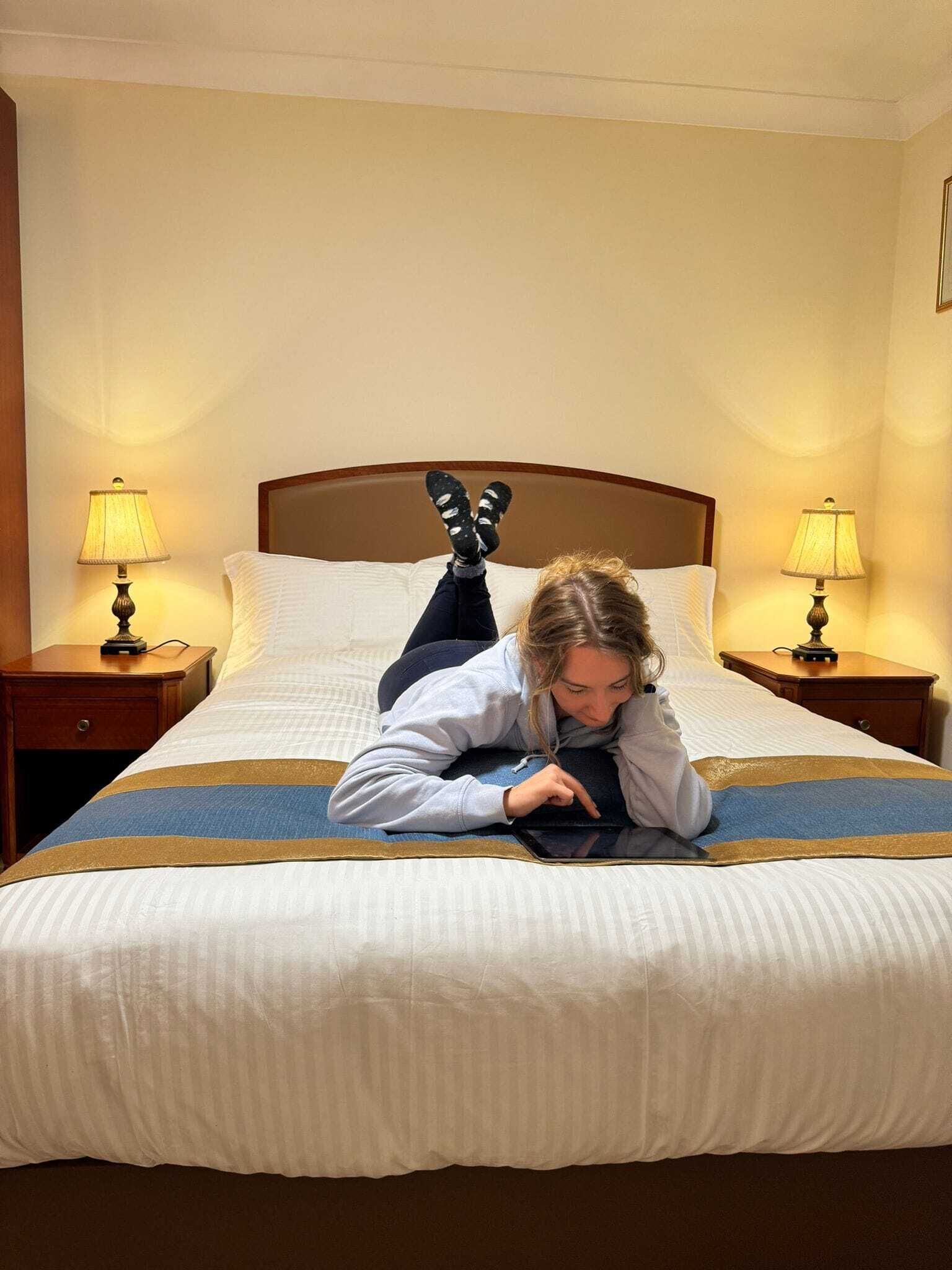 Ein Hotelzimmer mit einem Bett, zwei Nachttischen mit Lampen und einem Holz-Kopfteil.