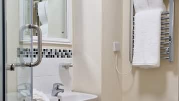 Ein Badezimmer mit Duschkabine aus Glas, Waschbecken in Weiß, Spiegel, Handtuchhalter und Toilette.