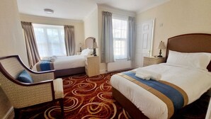 Een hotelkamer met twee bedden, een bureau en een stoel.