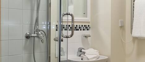 A modern bathroom with a glass shower enclosure, a white sink, and a mirror above it.