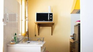 A compact kitchen with a microwave, sink, and small refrigerator. - Studio Calme Chaleureux (Brive-la-Gaillarde)