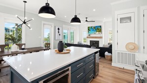 A modern kitchen with a large island, pendant lighting, and a view of the outdoors.
