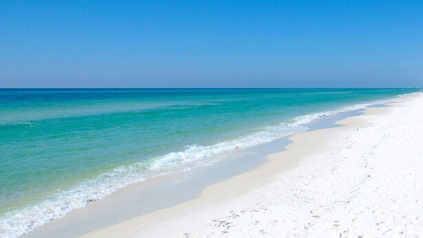 Une plage à l’eau turquoise et limpide et au sable blanc.