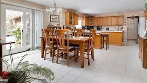 Une cuisine spacieuse avec des meubles en bois, un coin repas comprenant une table et des chaises, et une grande fenêtre laissant entrer la lumière naturelle.