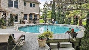 Une maison à deux étages avec une piscine, du mobilier d’extérieur et des plantes en pot.