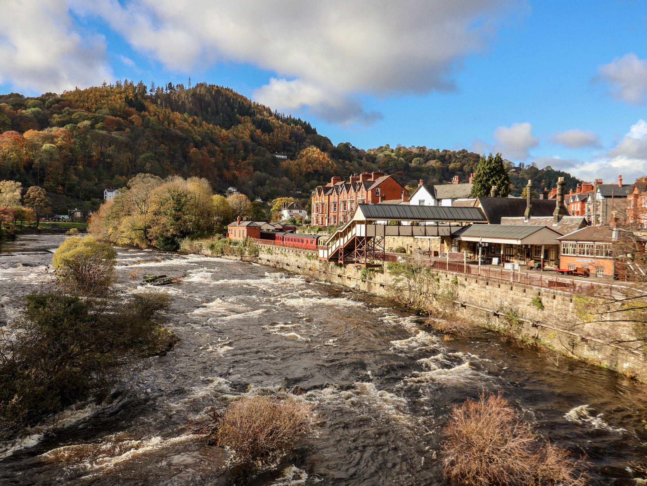 A river with a bridge and buildings, including a station with a covered waiting area.