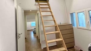 A narrow hallway with a wooden ladder leading to a loft area. - Villa Albani welcome house (Roma)