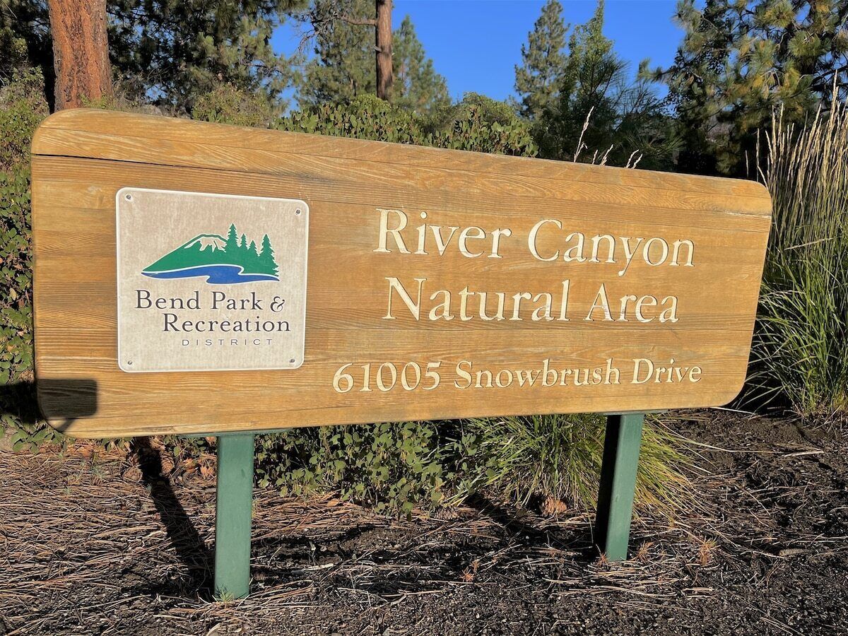 A wooden sign for River Canyon Natural Area with a Bend Park & Recreation District logo.