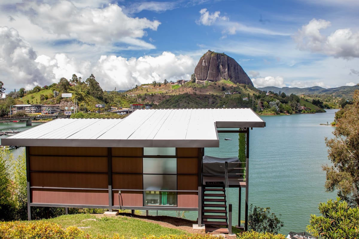 A modern building with a flat roof, a staircase, and a view of a lake and mountains.