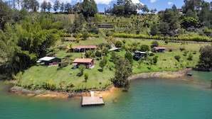 A lakeside property with multiple buildings, a dock, and lush greenery. - Cabañas Navegar (El Peñol)