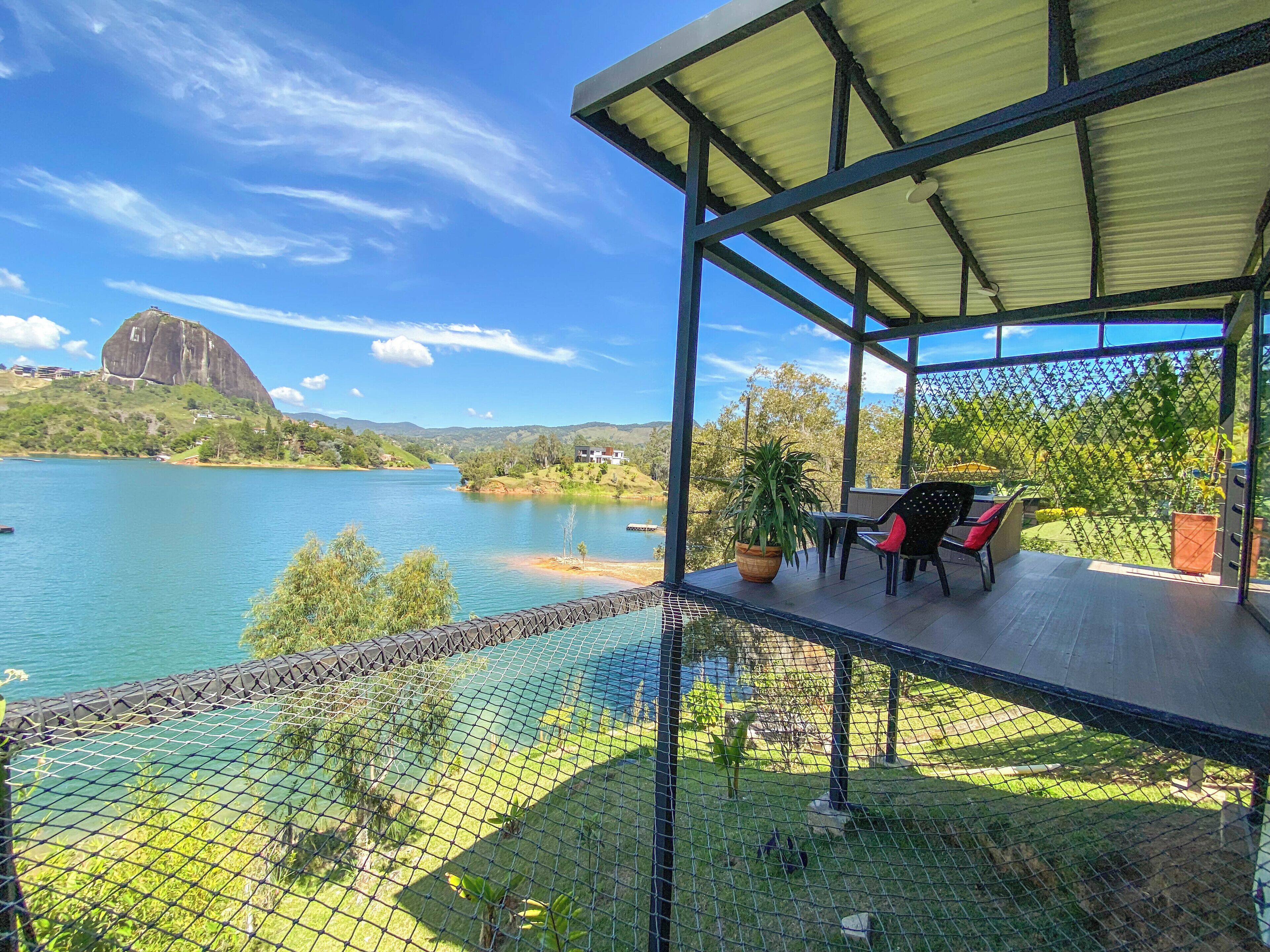 A covered outdoor seating area with a view of a lake and a mountain.