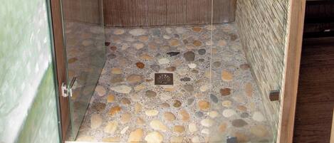 A shower with a wooden door and a pebble-patterned floor.