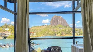 A room with a view of a large rock formation and a body of water. - Cabañas Navegar (El Peñol)